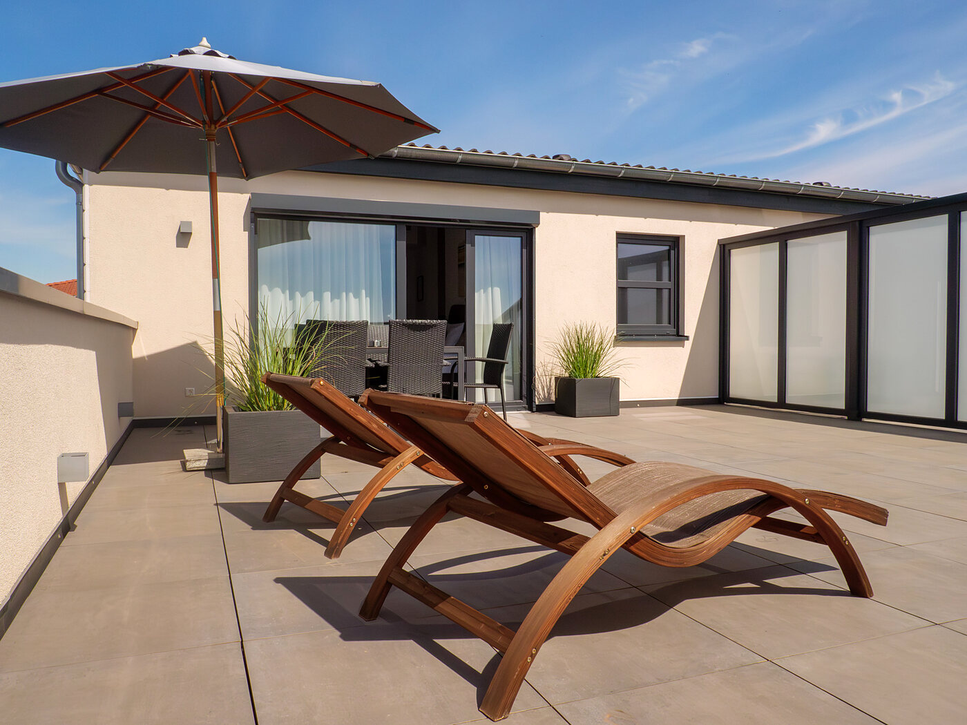 Dachterrasse des Hotels Sleep & Dream mit Holzliegen und Sonnenschirm