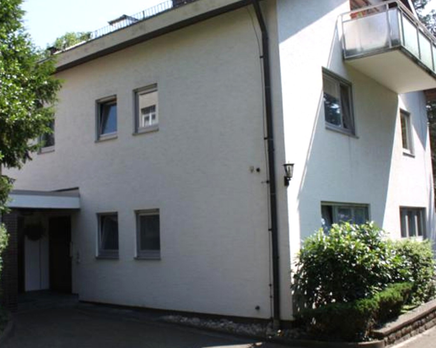 Hofseite des Hauses in Lahr vor der Kernsanierung: Backstein-Windfang, Flachdach mit Geländer, alter Putz