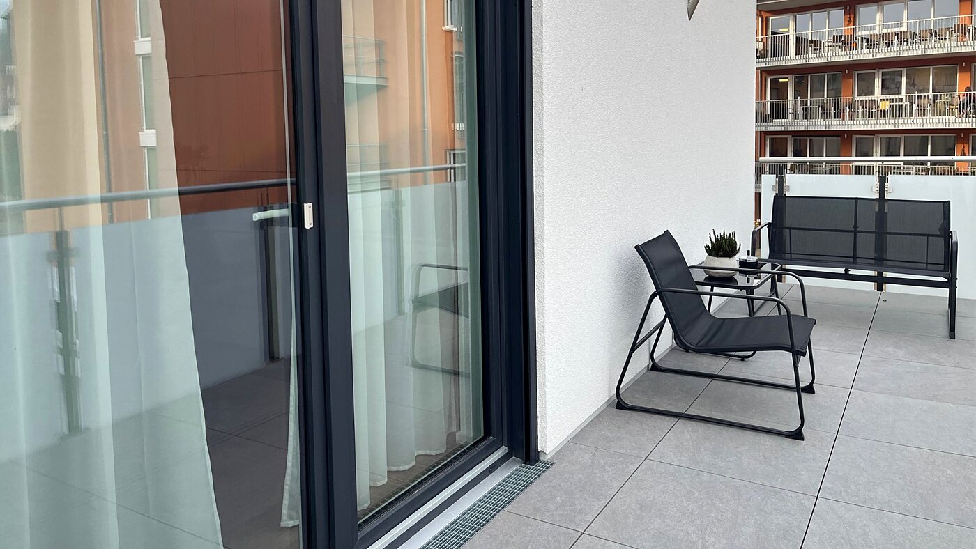 Balkon im Neubau Lahr mit Sitzgruppe und bodentiefer Schiebetür